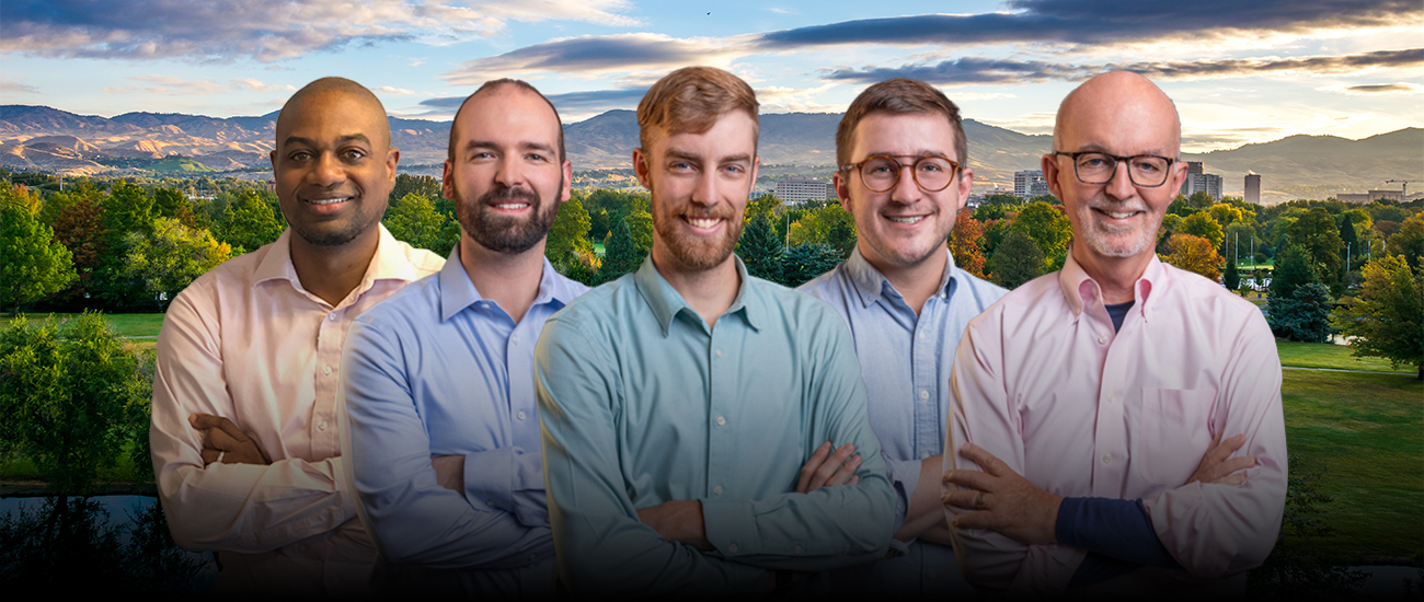 A group photo of Peters Patchin & Monaghan standing in front of a scenic background featuring a park with trees and a city skyline with mountains in the distance.