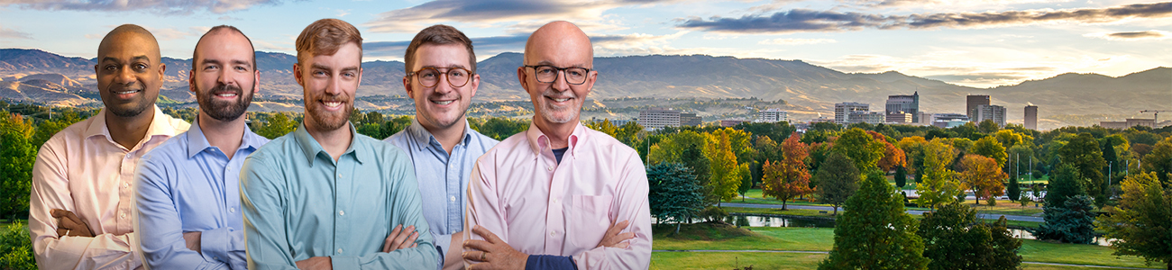 A group photo of Peters Patchin & Monaghan standing in front of a scenic background featuring a park with trees and a city skyline with mountains in the distance.